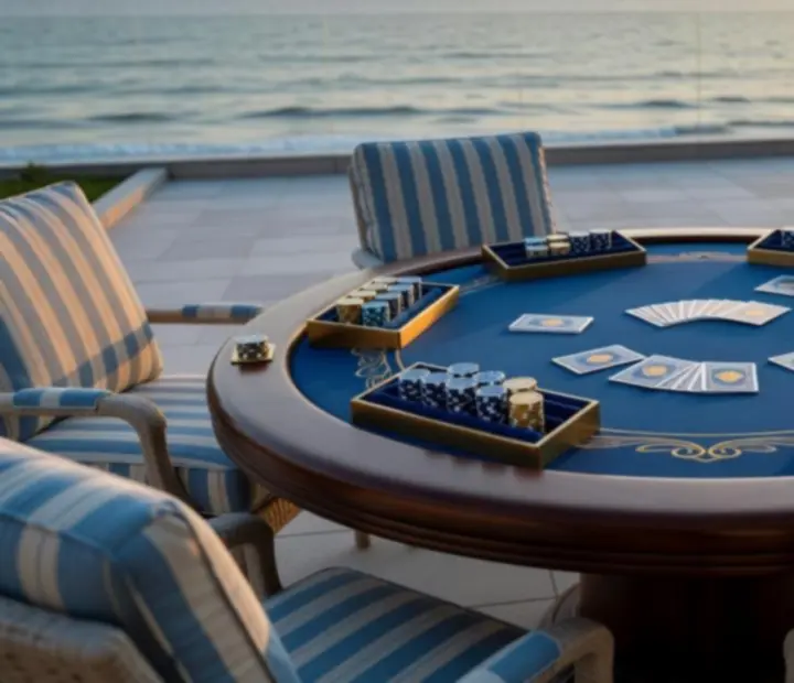 Sunset view of an outdoor poker table with chips arranged neatly on a coastal terrace.